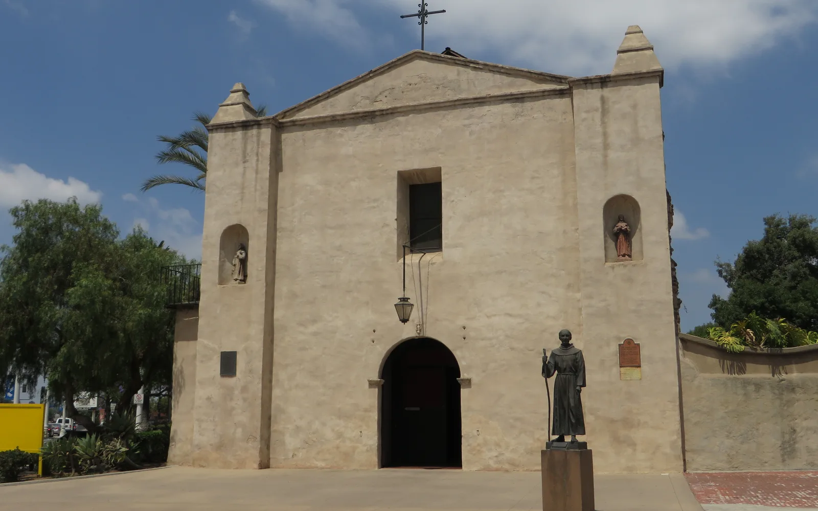 Historic Mission San Gabriel Arcángel with white adobe walls, bell tower, and entrance courtyard